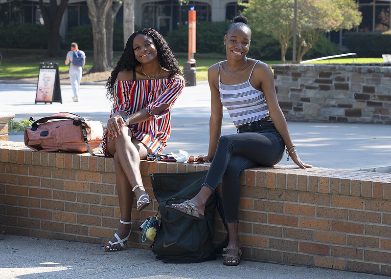 Two students smile for the camera in the middle of campus.