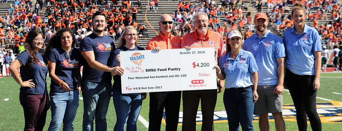 HEB presents check to food pantry at football game