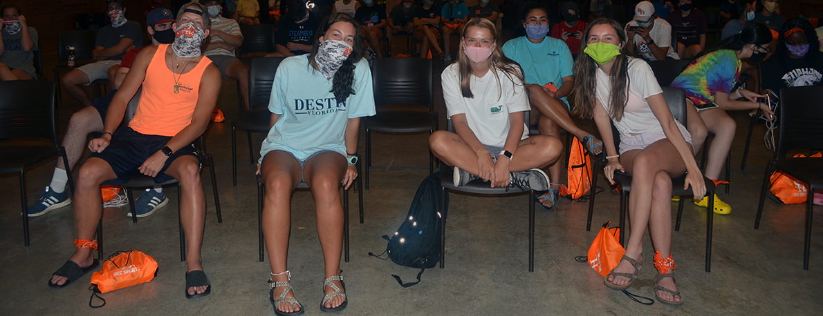 Campers sitting on chairs in lodge wearing facemasks