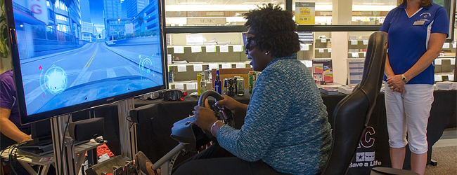 An individual playing a drunk driving simulator.