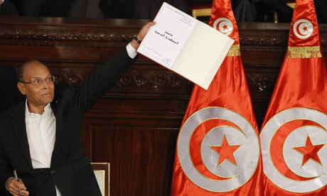 Tunisia's president, Moncef Marzouki, holds a copy of the new constitution after signing it before deputies in the national assembly on Monday. Photograph: Anis Mili/Reuters