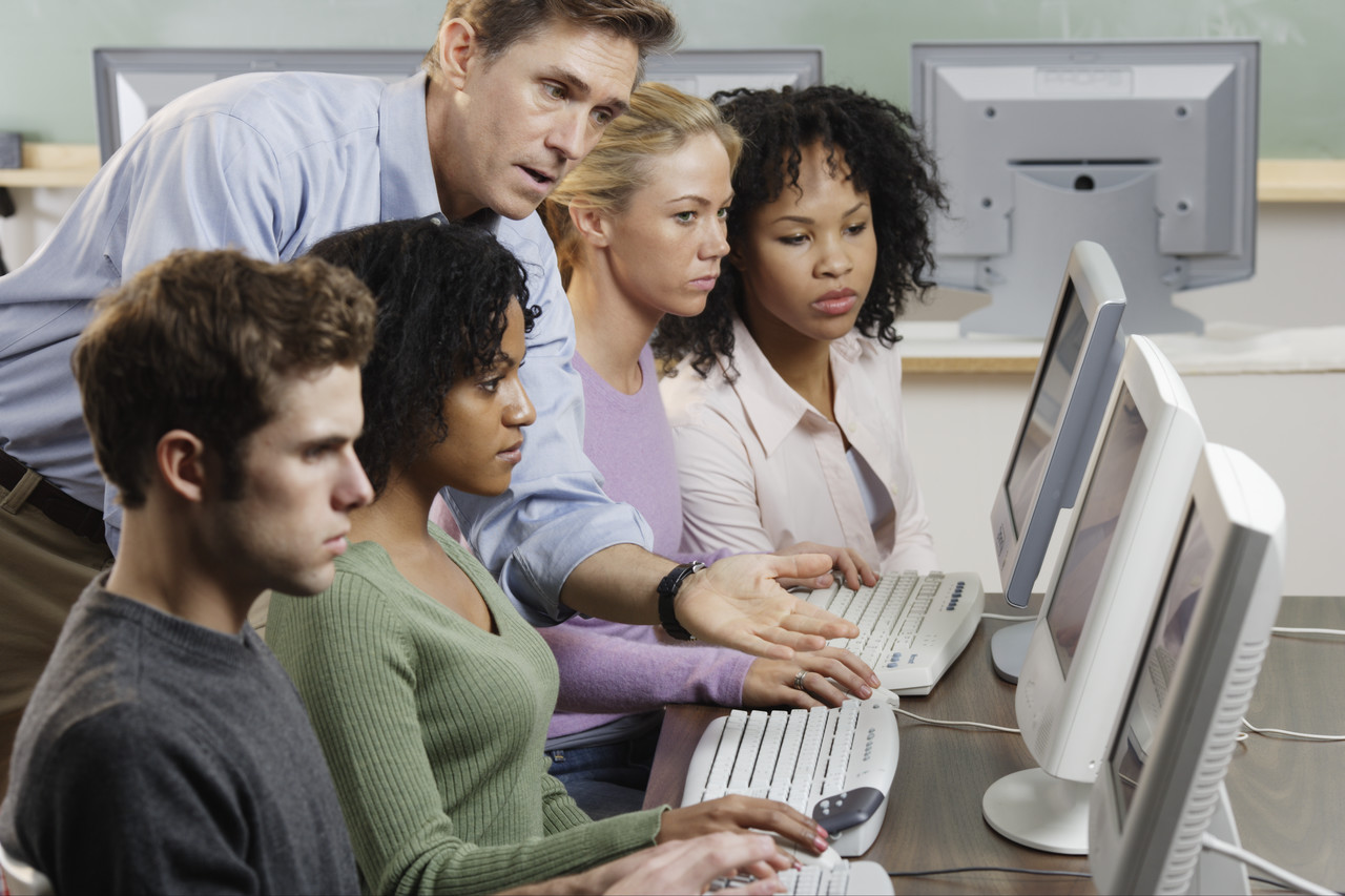 Professor assisting students with computers