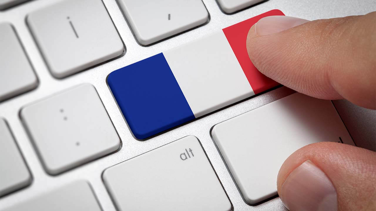 A man's fingers on a computer keyboard pressing a button colored like the French flag.