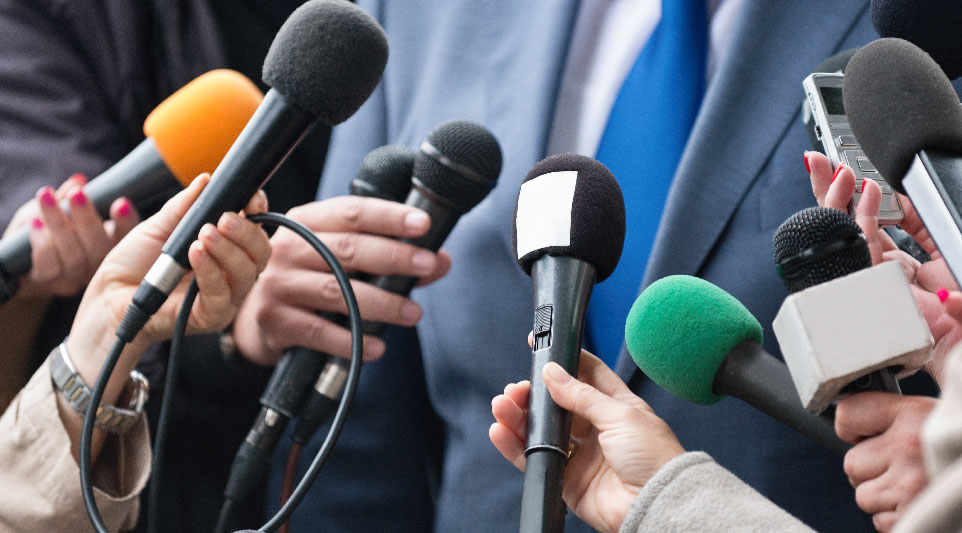 A public relations specialist speaking into multiple microphones.