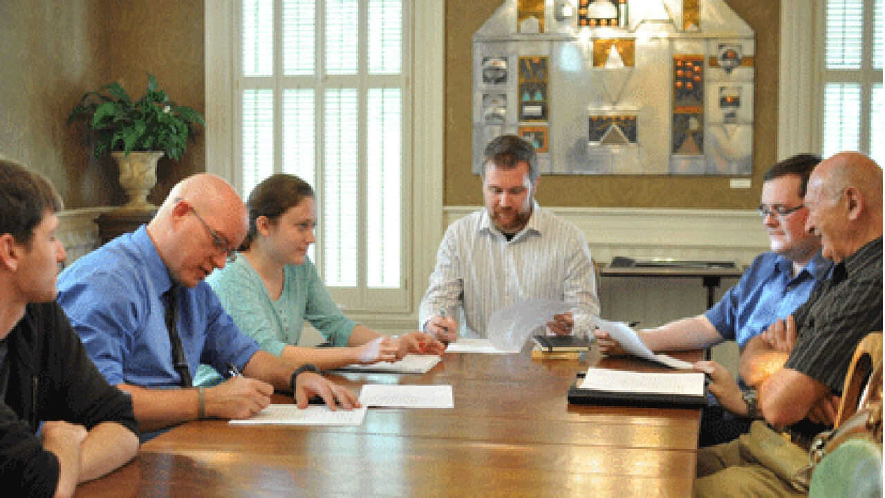 A group of professional men and women working together at a conference table.