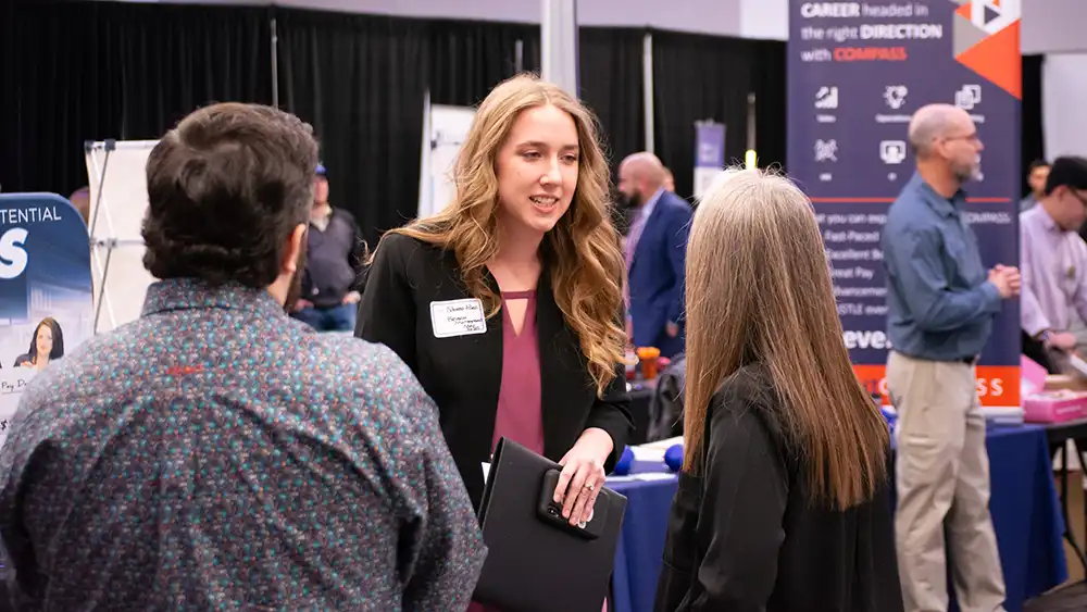 A woman meeting with recruiters at a job fair.