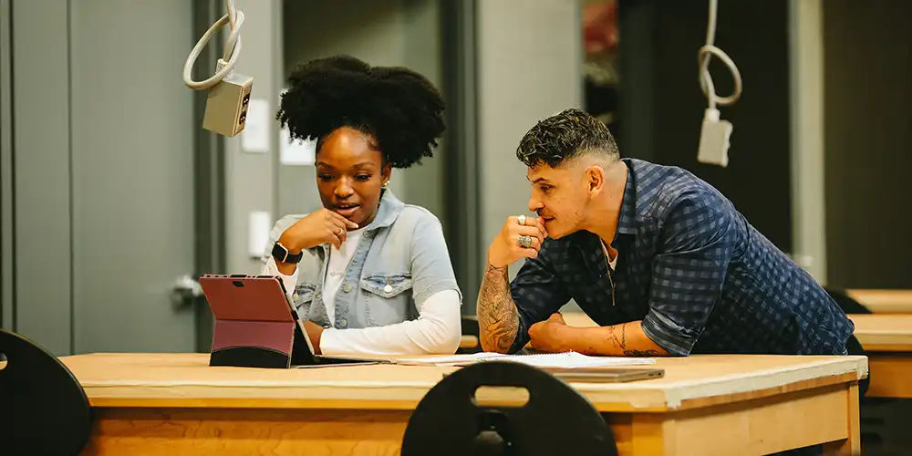 Two students looking at a tablet in a lab.