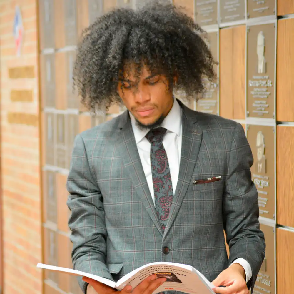 COBA student reading in front of plaques.