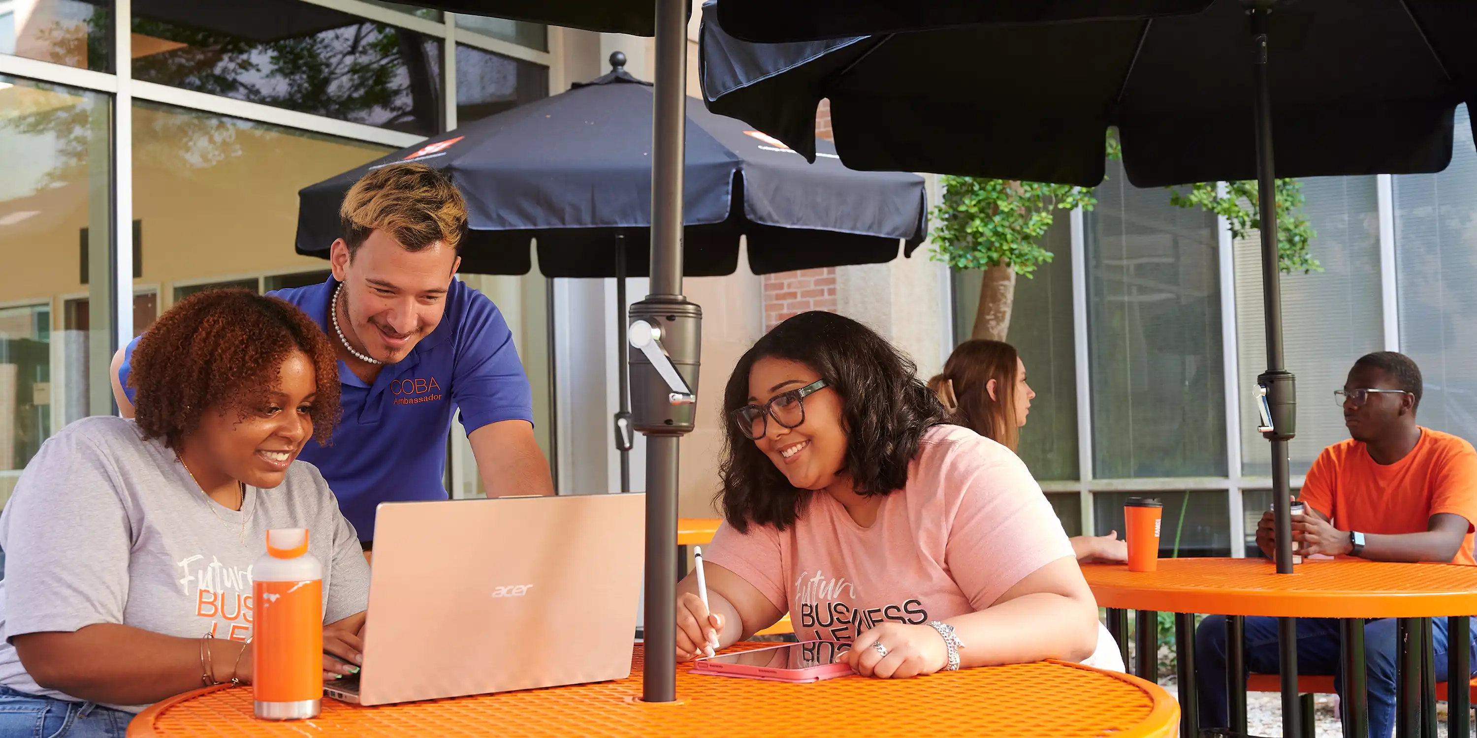Three students looking at a screen with College of Business shirts.