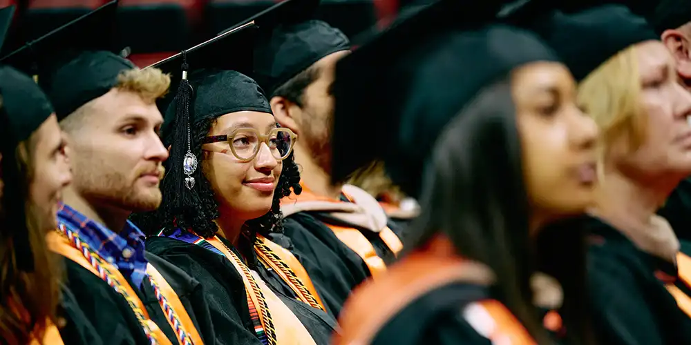 Students sitting in commencement, listening during the event.