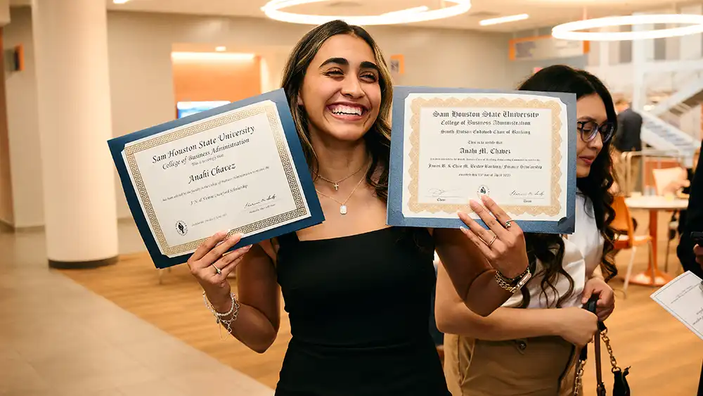 Anahi Chavez posing with their scholarship awards with their parent nearby.