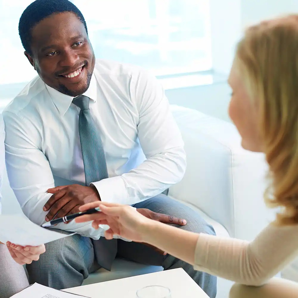 Man meeting with a woman in a business setting, smiling.
