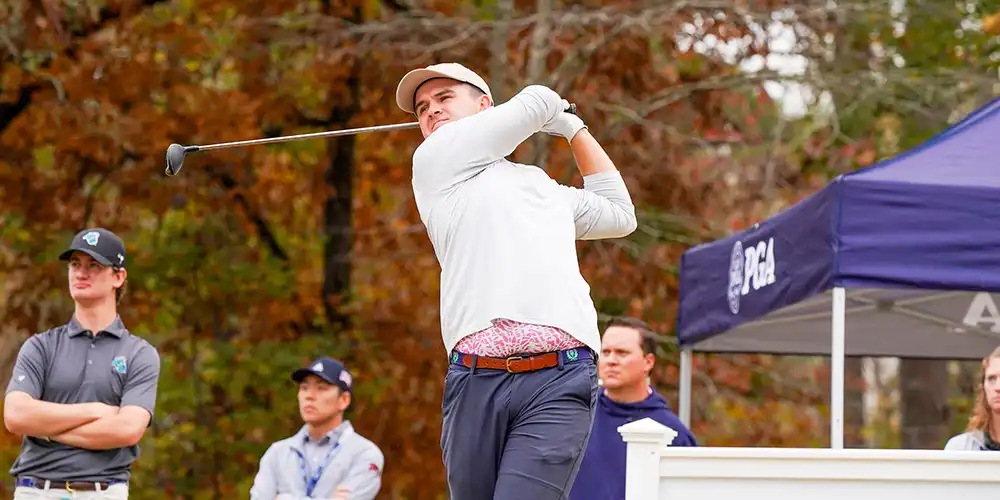 Golf student mid shot on a golf course.