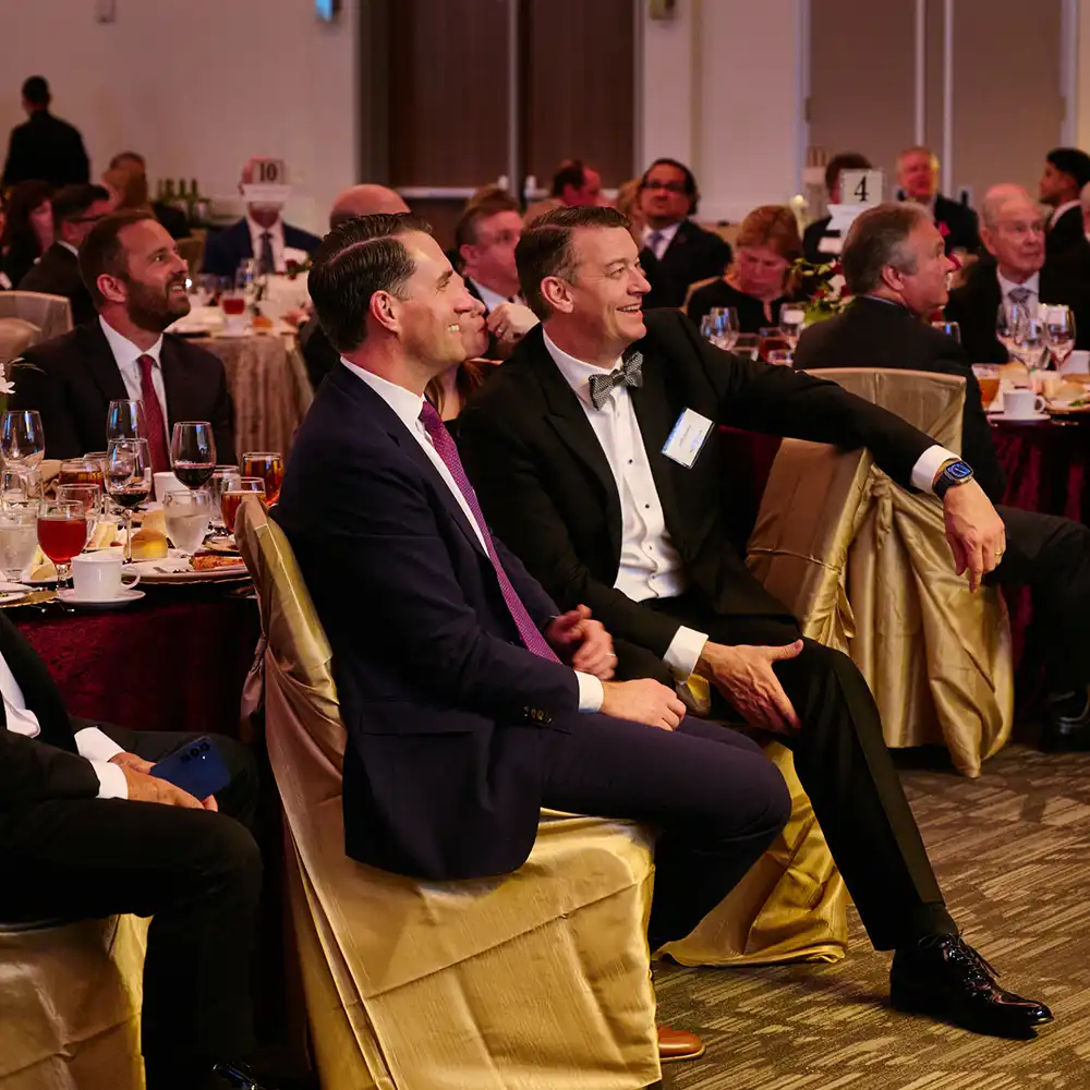 Men at the gala sitting and smiling during the presentation.