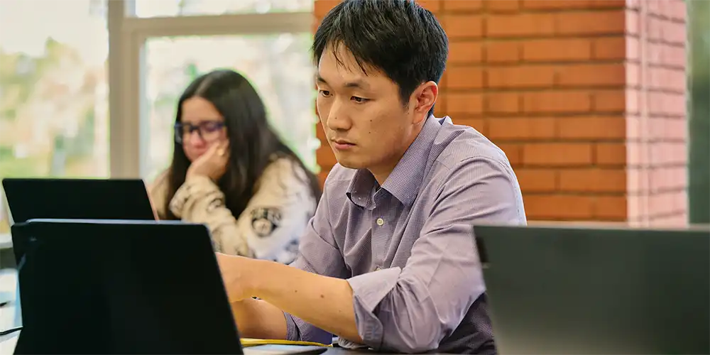 Graduate student working on laptop computer in classroom
