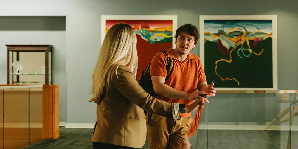 Department of Victim Studies professor points to laptop while student in classroom listen