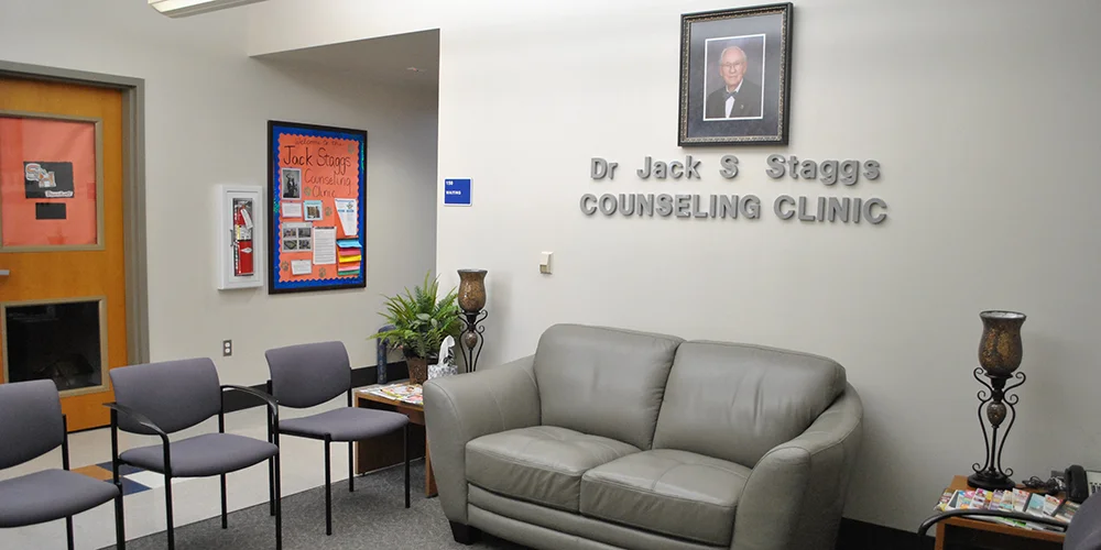  Sam Houston State University (SHSU) counselor education program, shows a student sitting on a blue couch speaking with a man in an armchair, simulating a counseling session