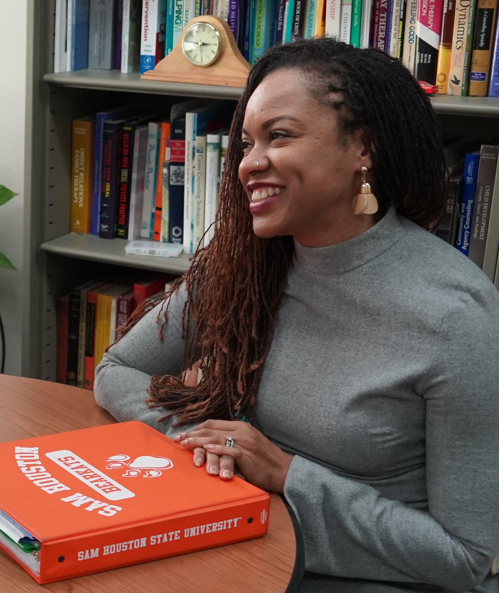 Two women looking at each other, smiling, sitting down, working on an assignment.