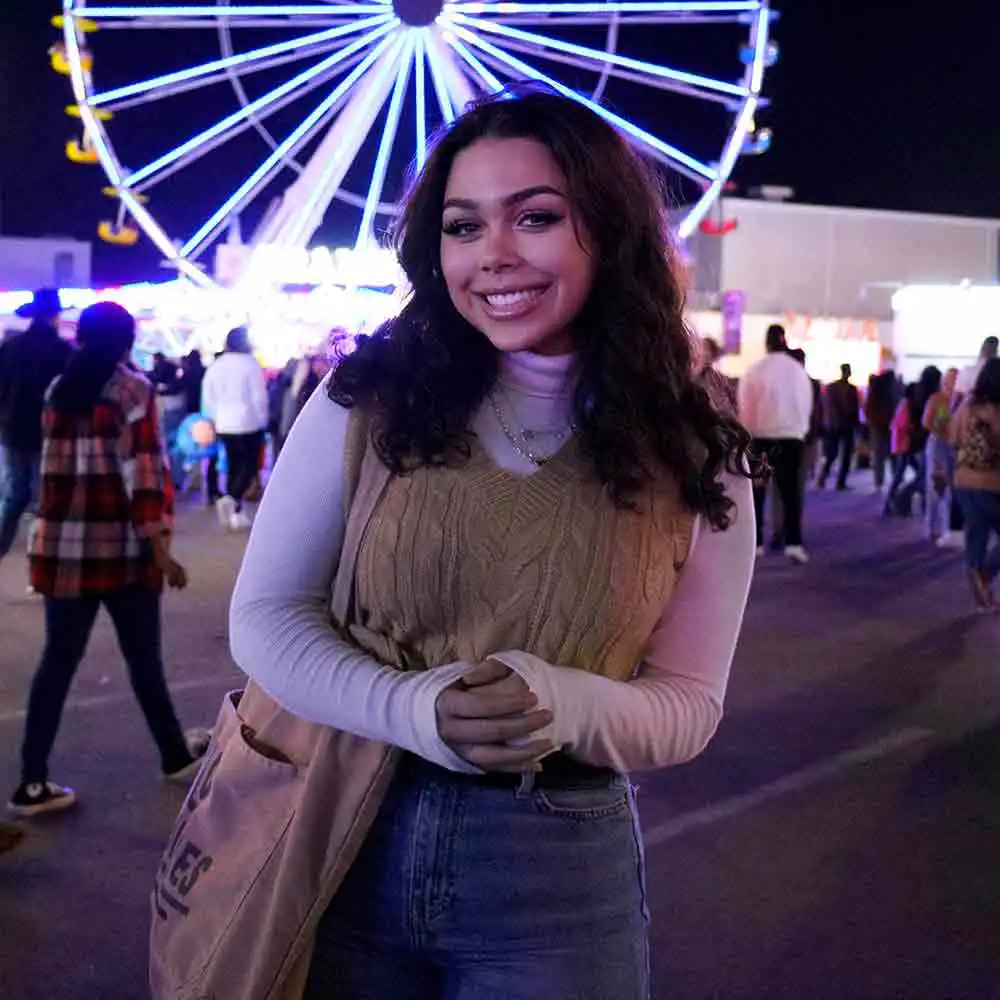 Amy Dellacrosse smiles with a ferris wheel behind her.