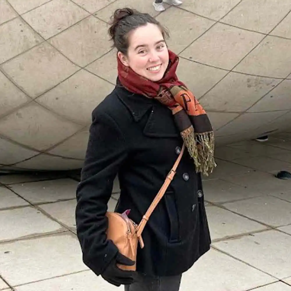 Tina Ellison stands smiling in front of a London landmark.