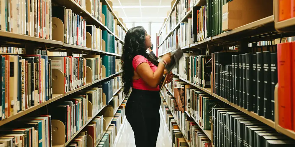 SHSU student browses through books in the Newton Gresham Library.