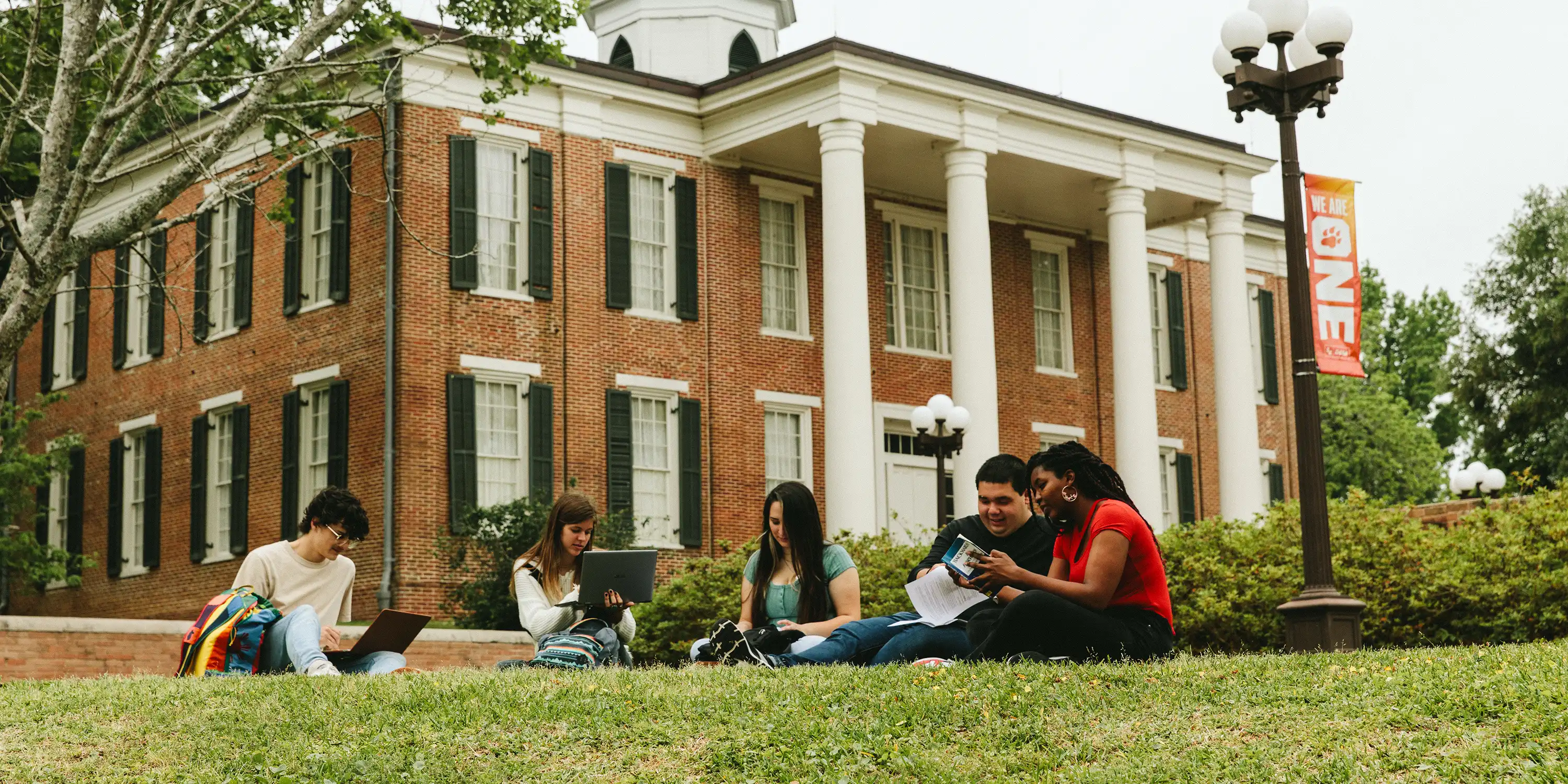 SHSU students sit on the lawn in front of Austin Hall reading and studying.