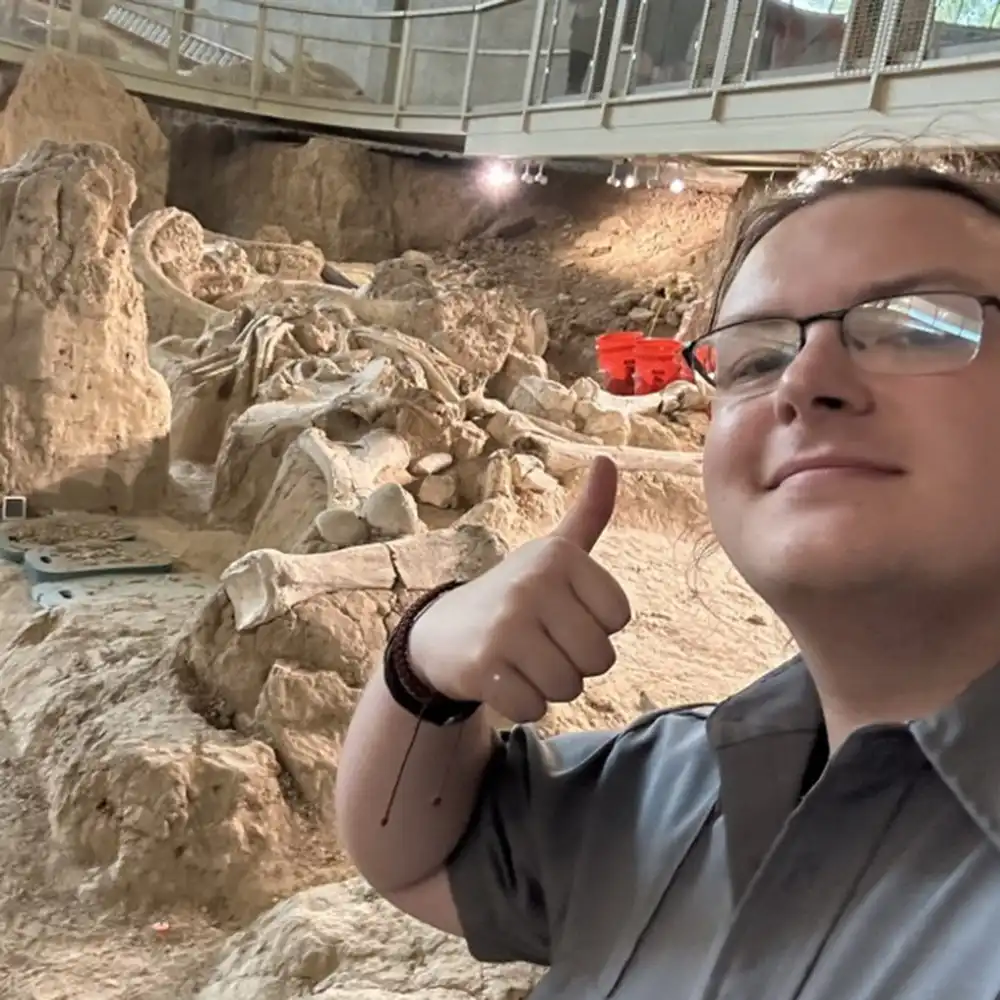 Ty gives a thumbs up posing by a fossil dig site.