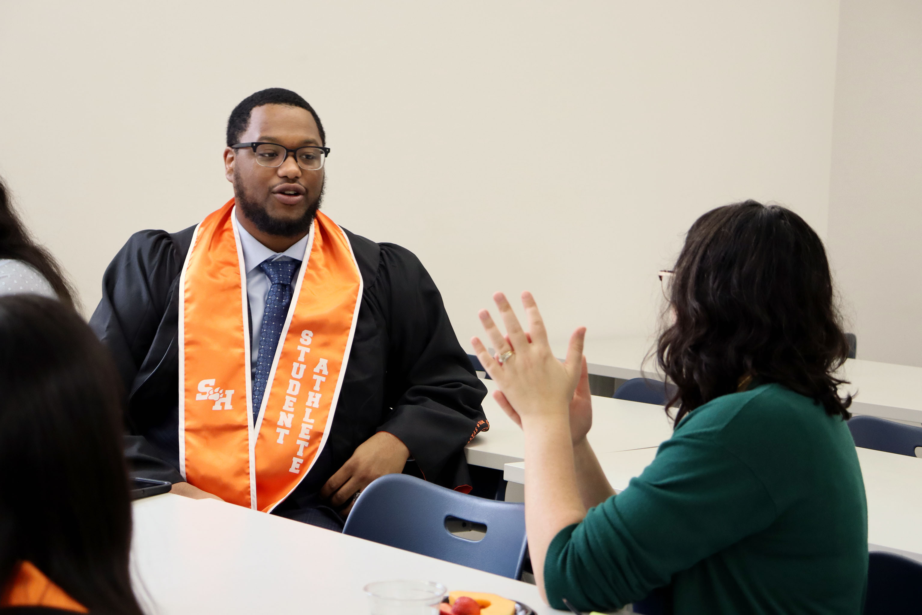 SHSU graduate speaks with faculty member at their commencement reception.