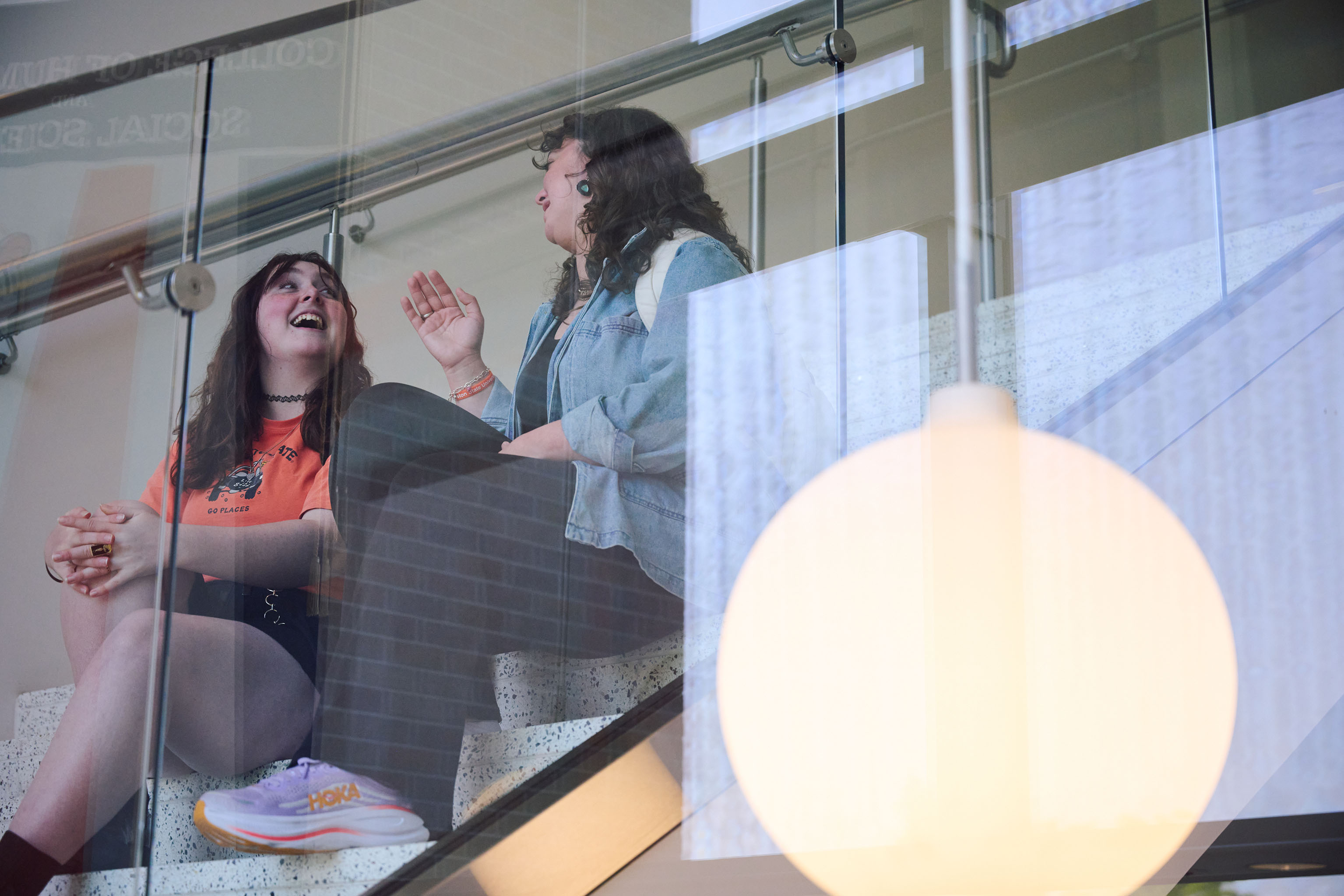 Two SHSU students sit on the CHSS building stairs deep in conversation.