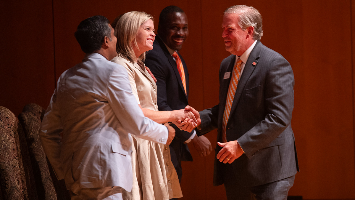 Staff and faculty honorees accept their service awards on stage. 