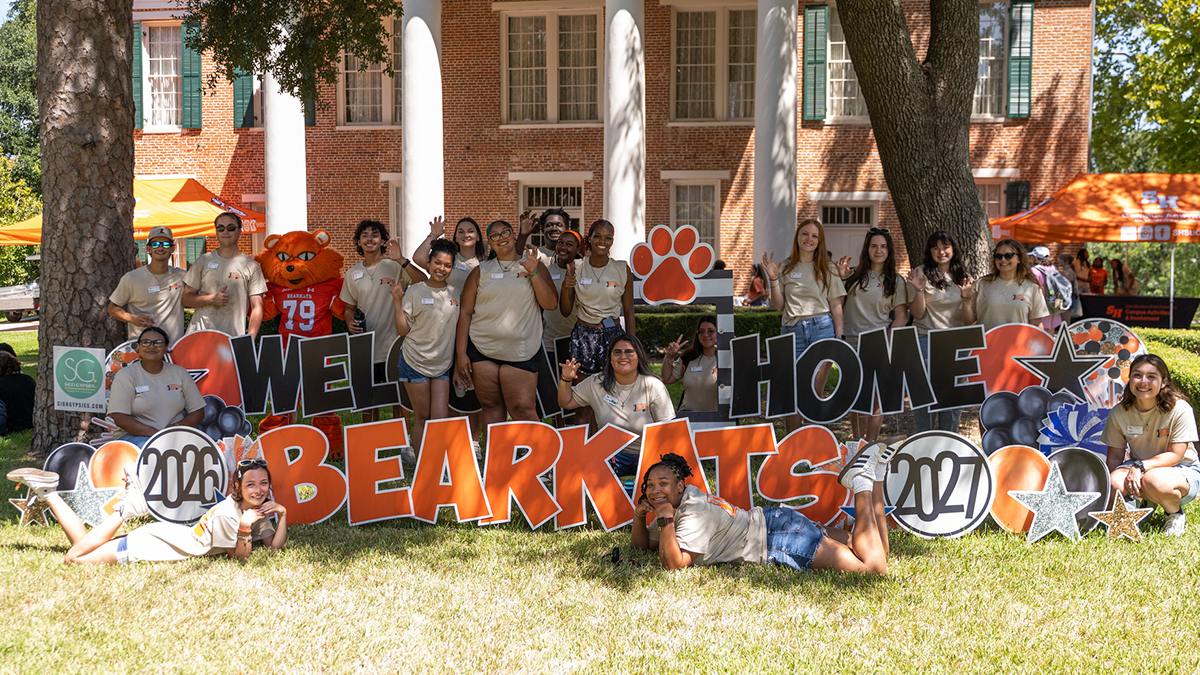 SHSU students pose by a sign that says Welcome Home Bearkats 2026-2027 during welcome week.