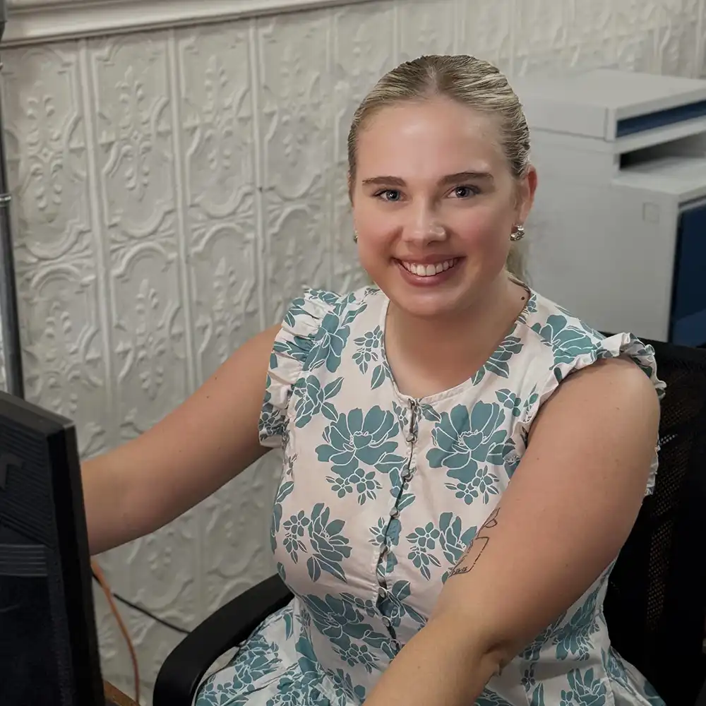 Brittlyn takes a moment to smile at the camera while working on her computer.