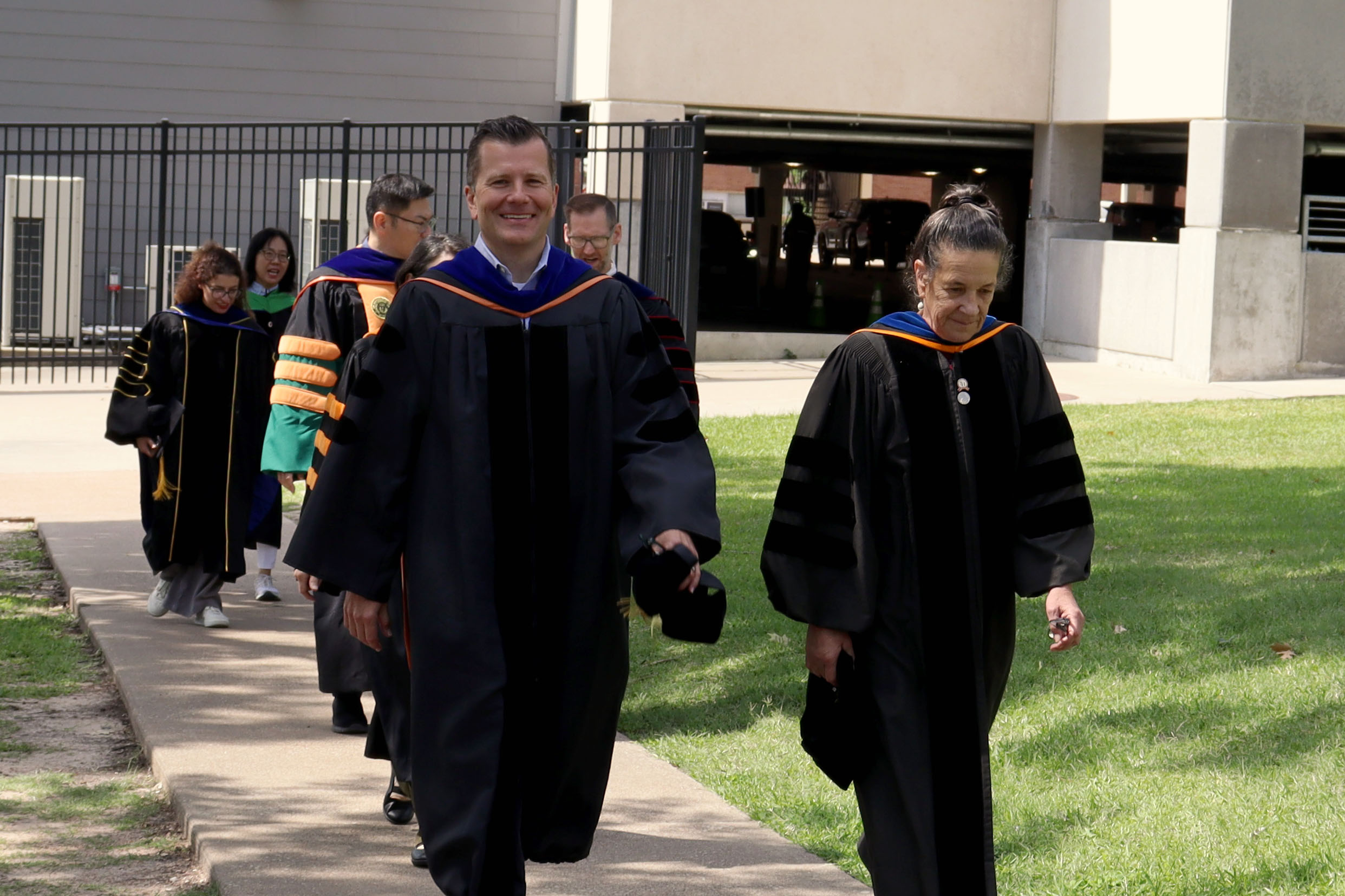 SHSU faculty walk back from commencement with proud smiles.