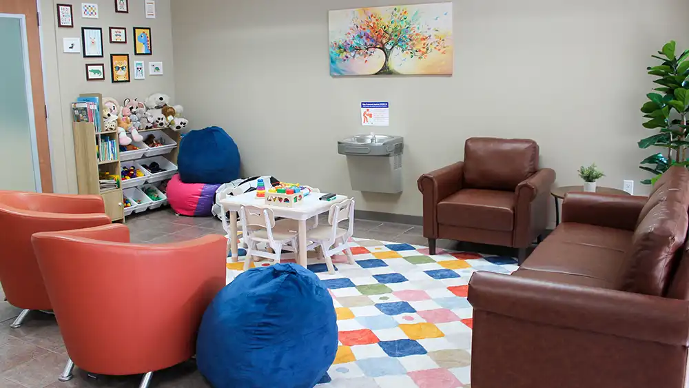 Waiting room of the Psychological Services Center showing a children's play area with bean bags, toys, and photos on the wall.