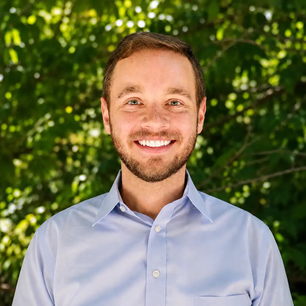 Dr. Ryan Marek smiles at the camera in a blue button up shirt.