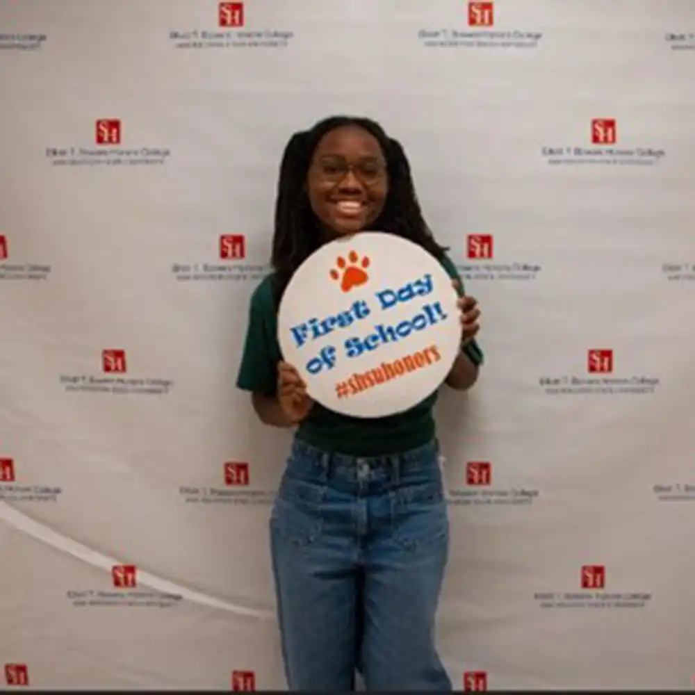 Kya poses with a big smile and 'first day of school' banner.