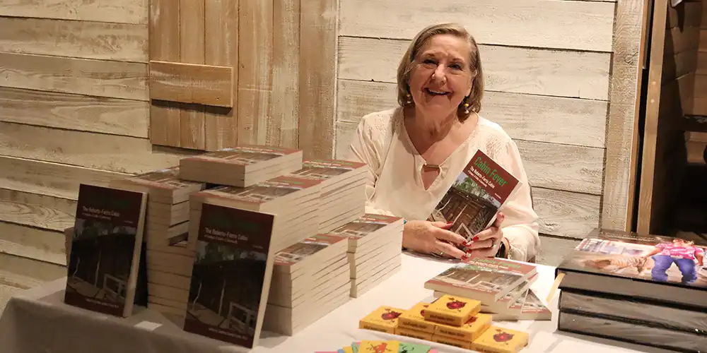 SHSU Emeritus HIstory Professor, Carolina Crimm, poses with her book which she published with the aid of students in an effort to save a log cabin in Huntsville.