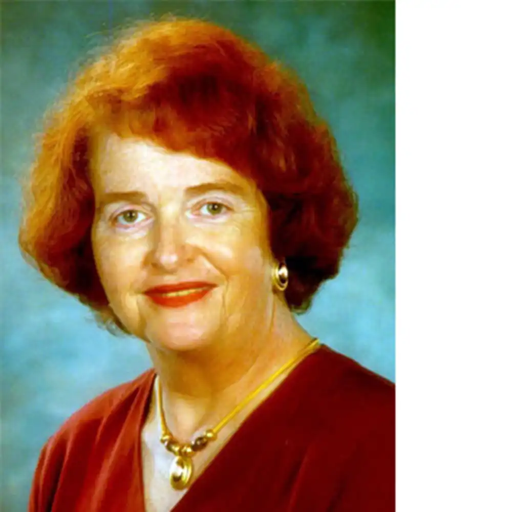 Smiling middle-aged white woman with red hair and a red blouse.
