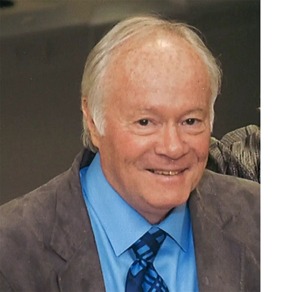 Smiling older while man in a brown suit and blue shirt.