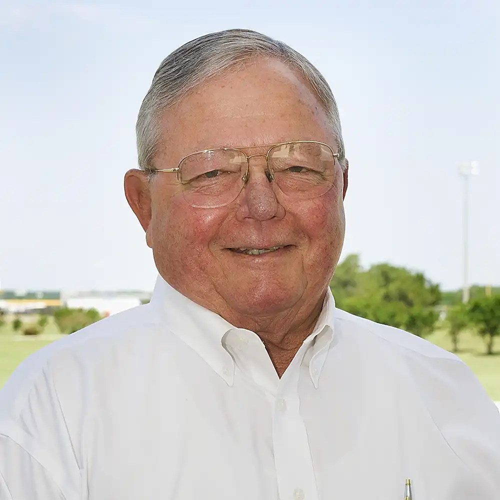 Smiling older white man in glasses and a white button-up shirt poses outside.