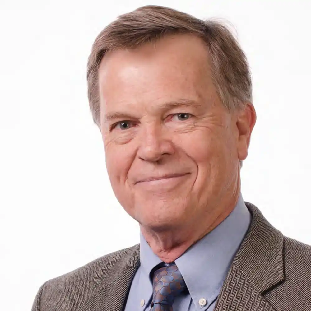 Smiling older white man in a brown suit.