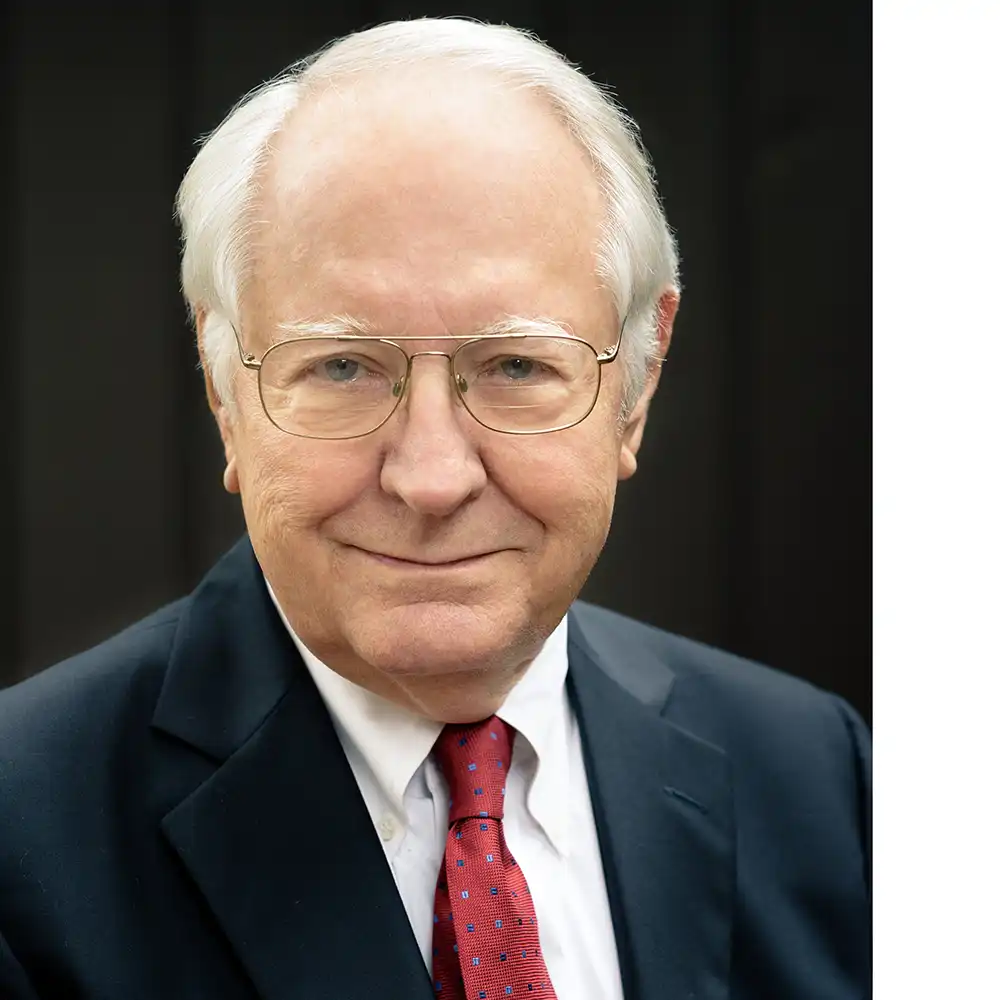 Grinning older white man in a suit and red tie.