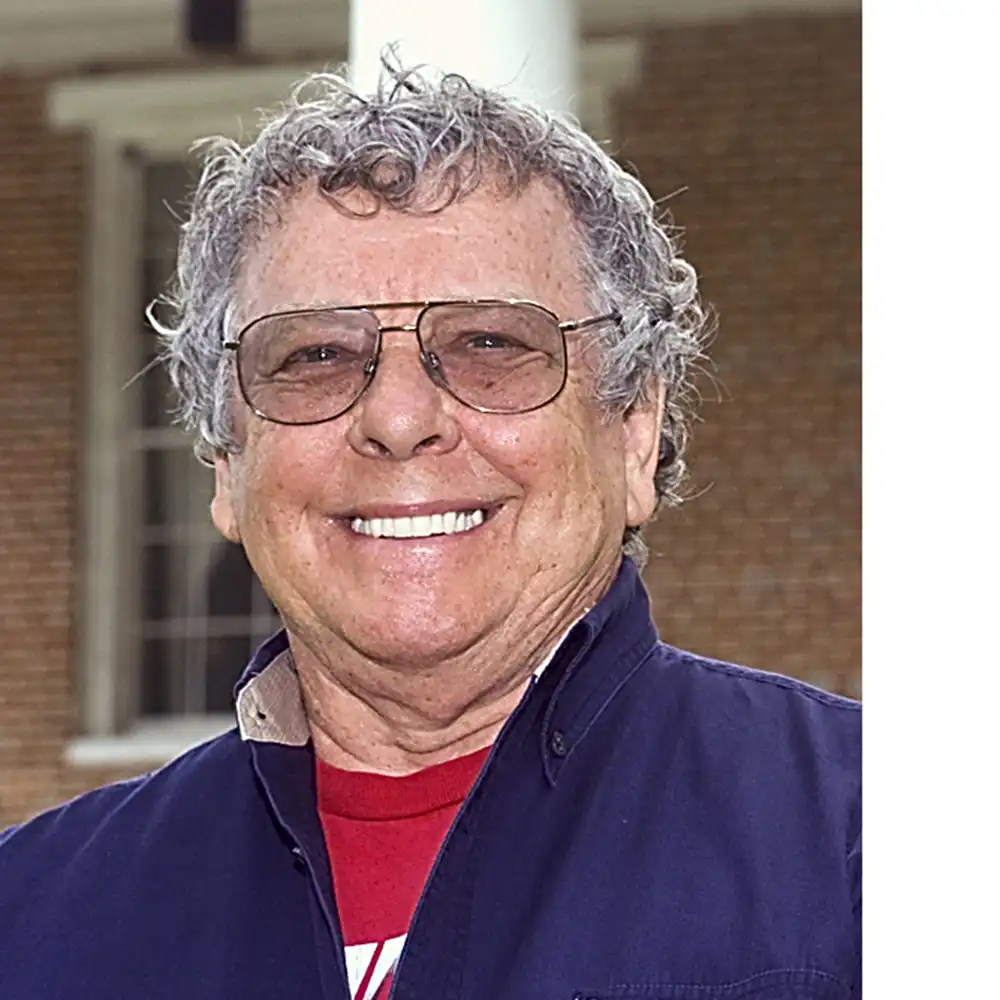 Smiling middle-aged white man with glasses wearing a blue jacket.
