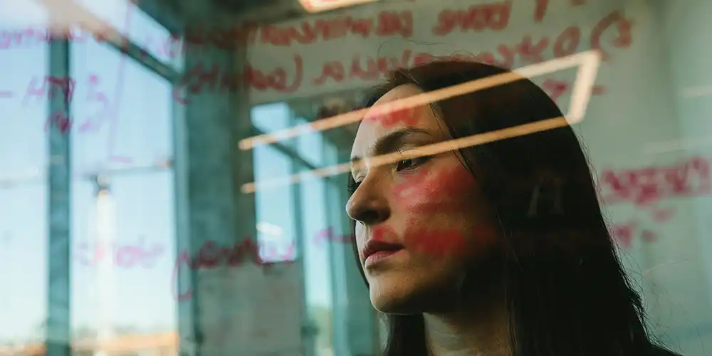 A view of a student through a glass window with writing on it