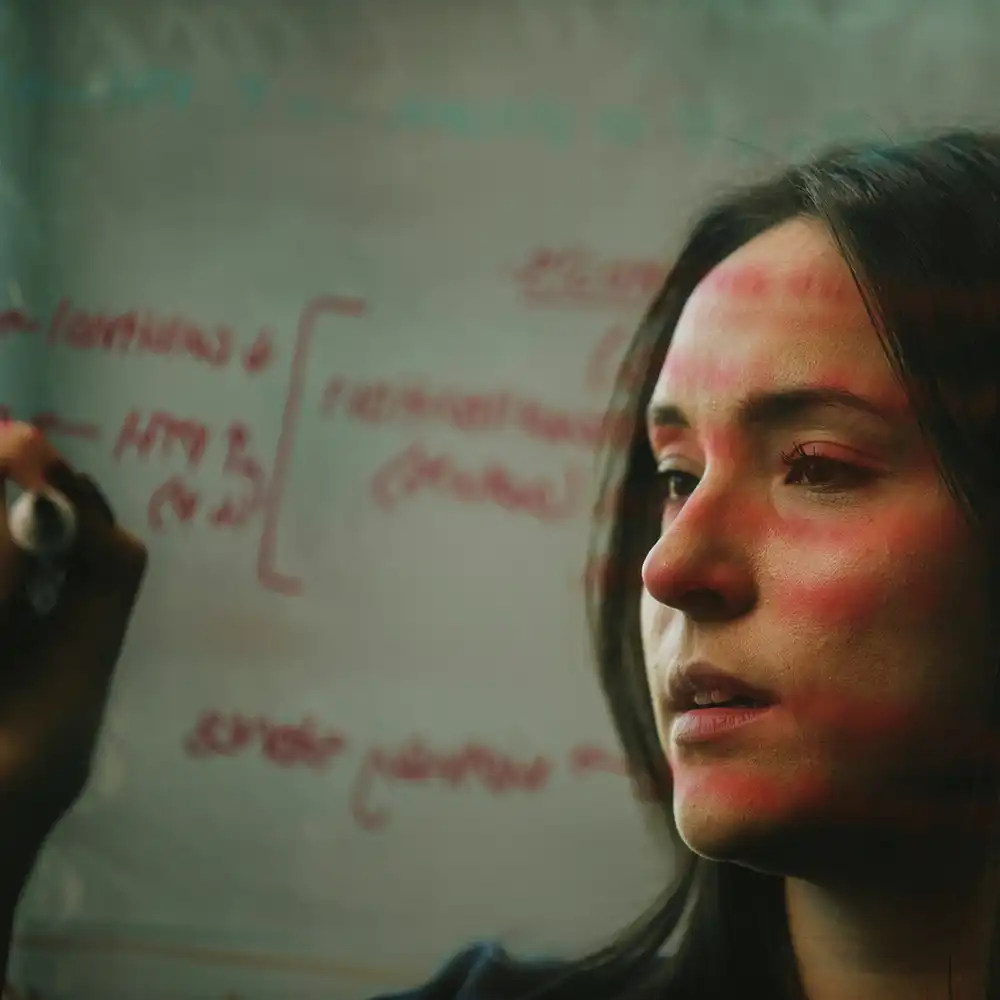 Professor at the front of a classroom lecturing to student doctors sitting at tables