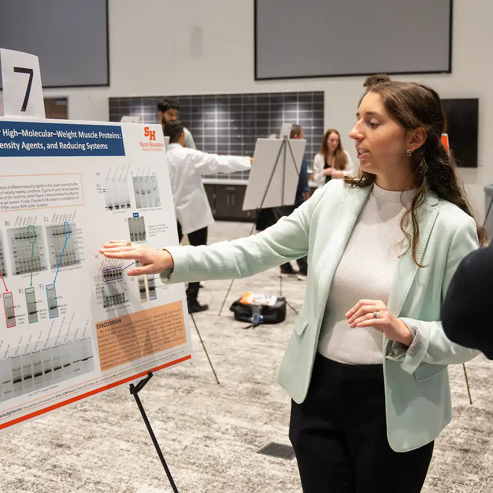 Student writing research results on glass with dry erase marker