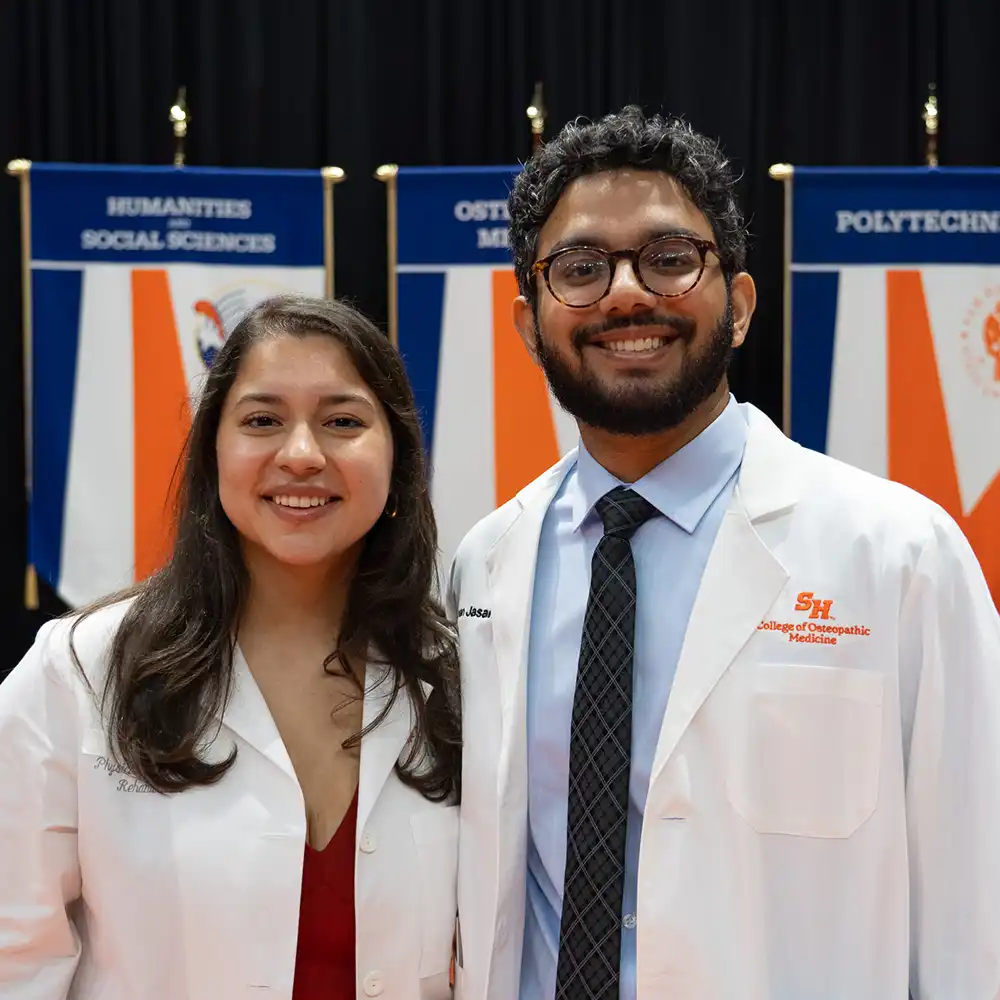 Doctor and student doctor standing next to each other and smiling at camera