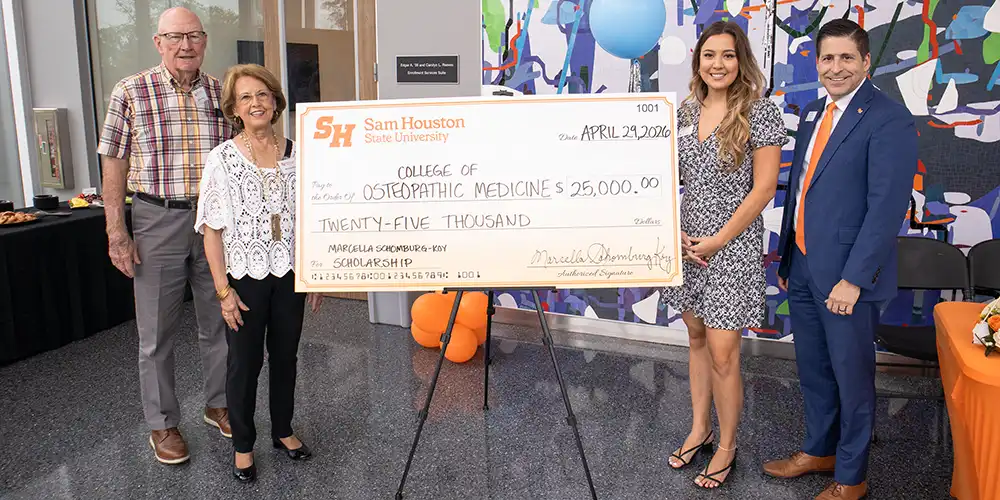 Group of people standing in front of large, $25,000 check