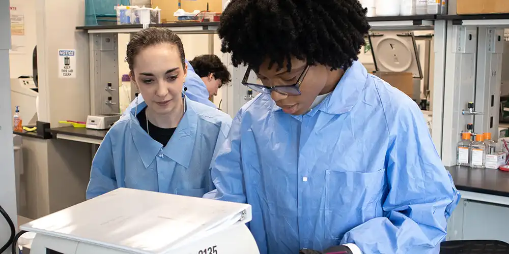 two students looking at scientific equipment in a lab