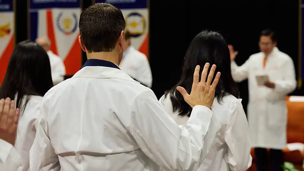 Student doctor's back with white coat on and hand in air like giving oath